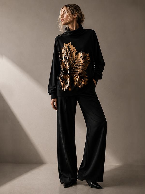 El Sweater Hoja Dorada transforma una prenda esencial en una pieza de diseño de autor. Su silueta amplia y relajada se combina con una intervención artística metalizada inspirada en las formas orgánicas de la naturaleza, generando un fuerte contraste entre el negro profundo y el brillo del dorado.

Su cuello amplio y el calce cómodo permiten llevarlo con pantalones sastreros, denim o cuero, convirtiéndolo en una prenda protagonista para el día y la noche.